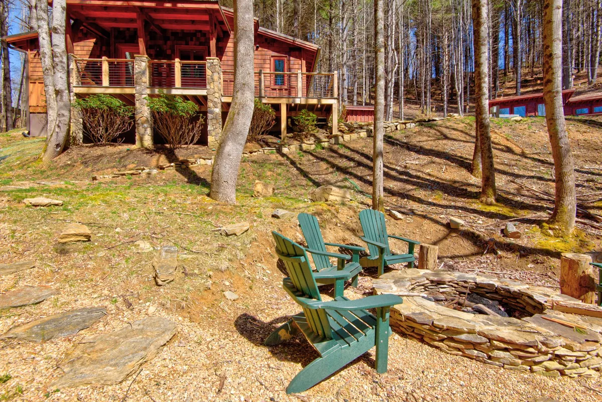This image features a cozy fire pit area with Adirondack chairs arranged around a crackling campfire, set against the backdrop of a charming wooden cabin nestled among the trees. The scene evokes the warmth of outdoor gatherings and invites families to share stories or roast marshmallows together under the stars.